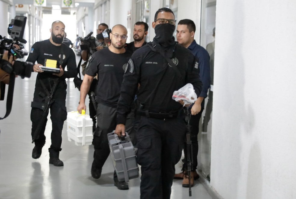 Policiais com material apreendido na casa de MC Poze do Rodo — Foto: Gabriel de Paiva / Agência O Globo